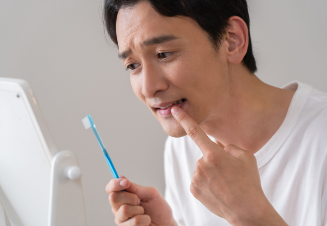 鏡で歯を確認している男性のイメージ